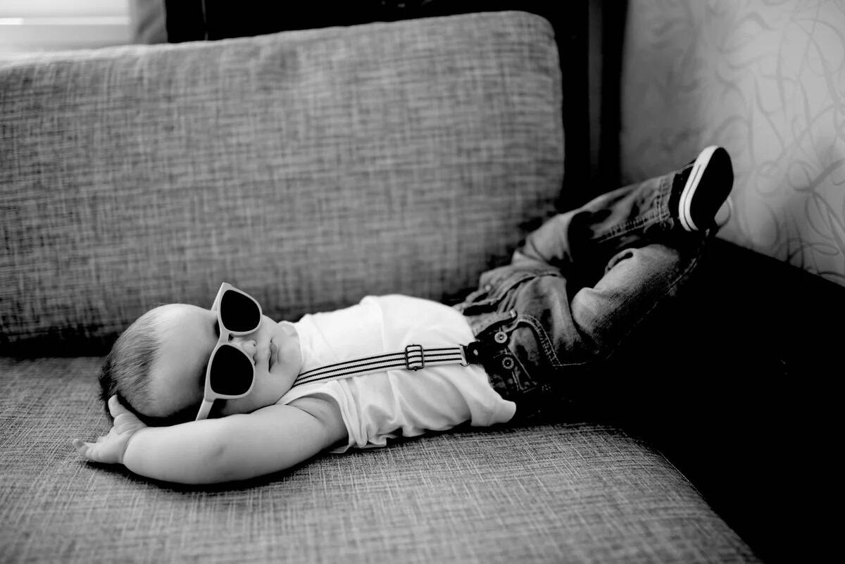 Baby boy wearing sunglasses lying on couch