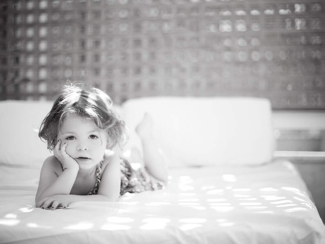 Toddler on bed resting head in palm